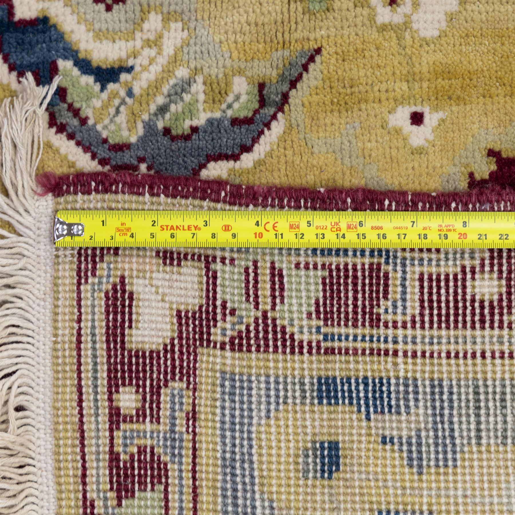 Agra design wool carpet, burgundy field decorated with large scrolling floral vines, palmettes and flowerheads, enclosed by blue main border with oversized stylised palmettes and narrow guard stripes