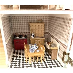 Georgian style wooden double fronted three-storey dolls house with pale blue stucco finish under a faux tiled roof with two chimney stacks, the double hinged front opening to reveal six fully decorated rooms with floor coverings, central staircase, porcelain fitted bathroom, kitchen with deep white sink and Aga cooker, electric lighting with adaptor, fully furnished with French style and other furniture, grand piano etc, and comprehensive range of accessories H82cm W61cm D31cm