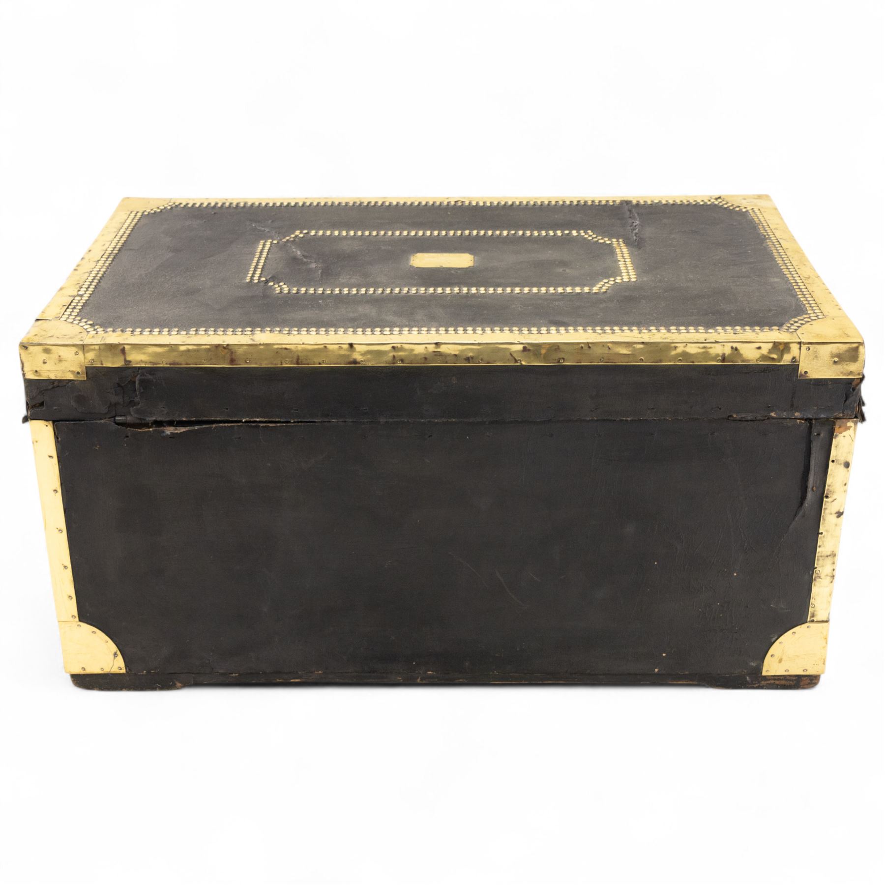 An early 19th-century Georgian brass-bound travelling trunk, leather-covered exterior with brass stud work decoration, front with central brass lock plate, hinged lid with camphor wood interior, external sides fitted with large brass carrying handles 