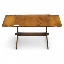 Early 20th century oak drop leaf cottage table, rectangular top with twin hinged leaves, on shaped trestle end supports united by central stretcher