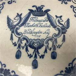 Early 18th century Delft marriage plate, of circular form with dished centre, the centre inscribed and dated 'Thomas and Elizabeth Kockerill Bridlington Key 1715' within a crowned C scroll cartouche, flanked by demi-griffins, above a putto head and tassels, within a wide foliate border, D34cm
