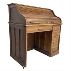 Early 20th century oak roll-top desk, the tambour enclosing pigeon holes and small drawers, the base fitted with slide, a single long drawer and three smaller drawers