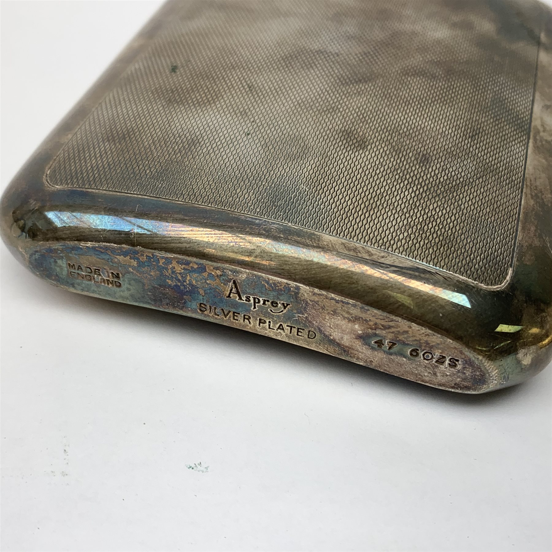 An Asprey silver plated hip flask, of rounded rectangular form with engine turned panel decoration to the front and back, the front panel with vacant rectangular cartouche to the upper left corner, H14.5cm, together with a gold plated Dunhill cigarette lighter with bark textured effect body, H6.5cm. 