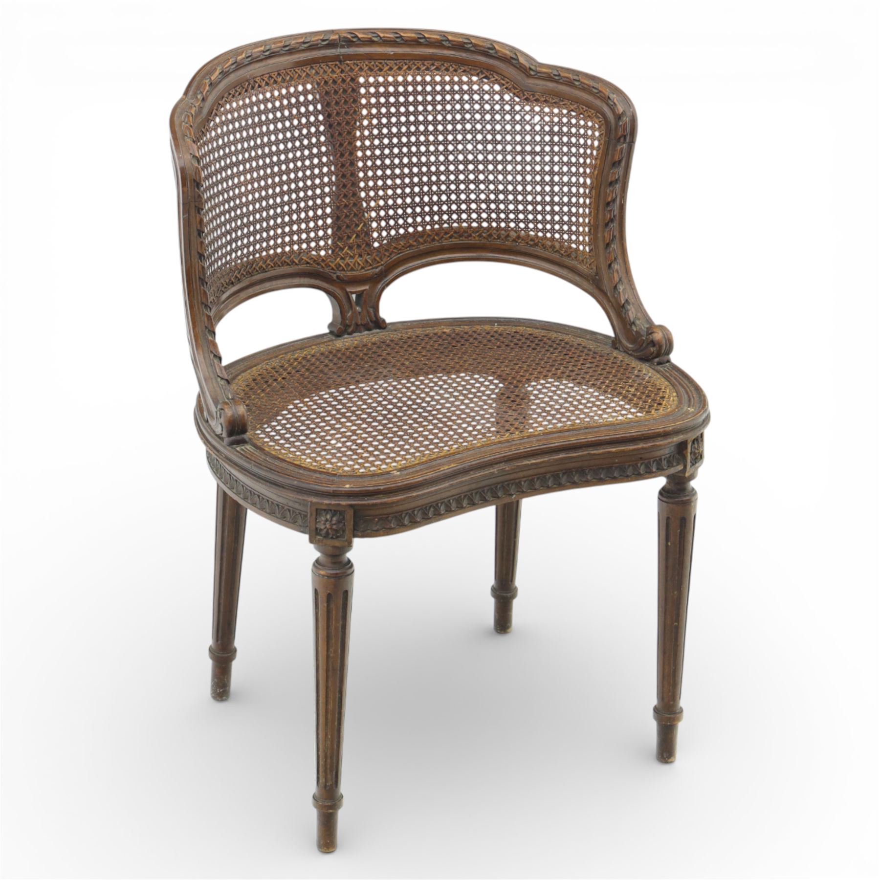 Late 19th century cane bergère armchair, the serpentine shaped back flowing into enclosed arms, the back and seat caned throughout, with carved detail to the crest and arm terminals, on turned legs