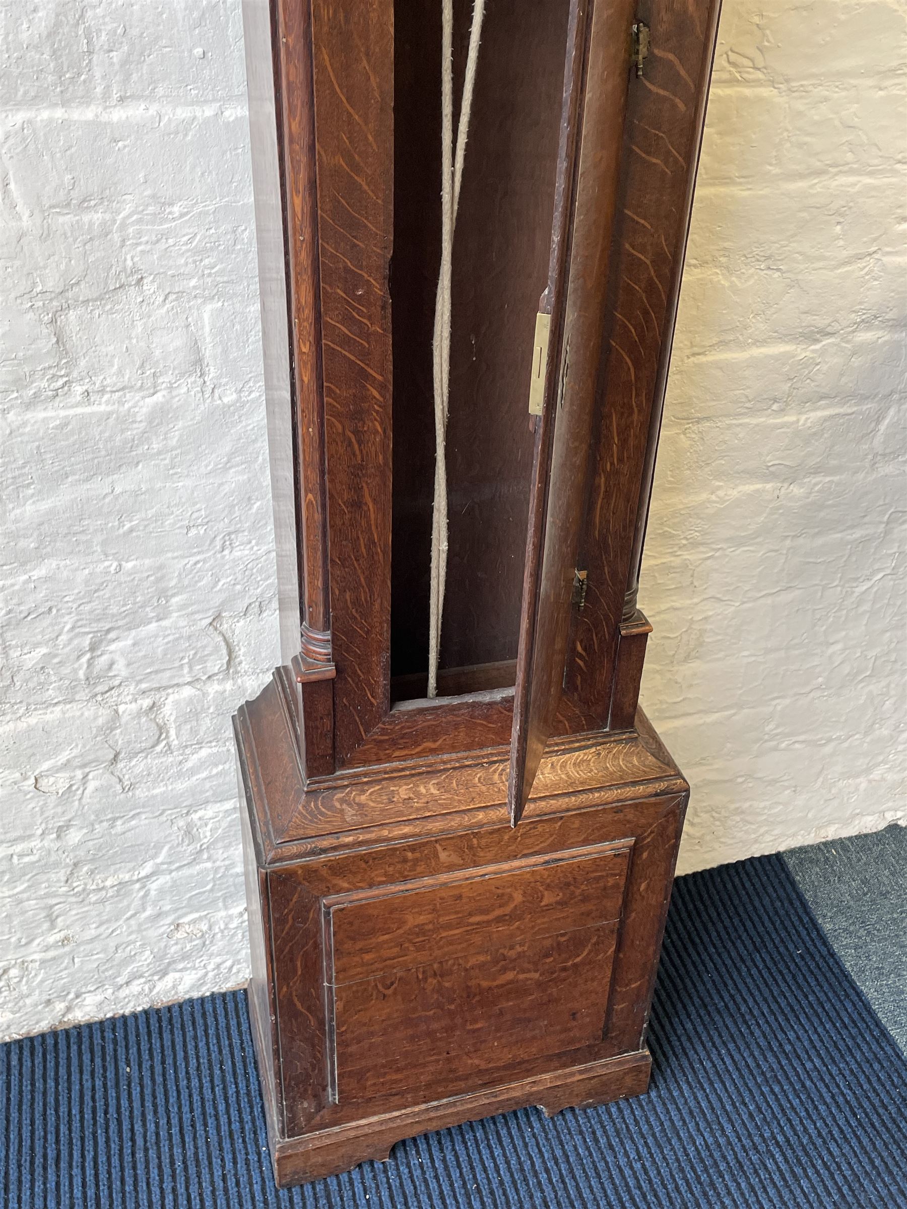 18th century c1760 oak cased George III longcase clock by William Eastwood of Burnley, with a stepped caddy top on a projecting cornice and blind frieze, square glazed door flanked by two turned pillars with gesso capitals, trunk with conforming recessed pillars and a full length wavy topped door, on a square plinth with a raised panel and shaped skirting, 12” square brass dial, 11” chapter ring with Roman numerals and five-minute Arabic's,  