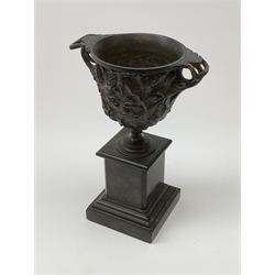 A bronze twin handled urn, cast with acanthus leaves and buds, raised upon a marble plinth with stepped base, (a/f), H25cm