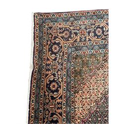 Persian Bidjar peach ground carpet, central pole medallion enclosed within lozenge field and spandrels, decorated all over with small Heratti motifs, the main border with trailing pattern decorated with stylised plant and Boteh motifs, within two triple band guard stripes with repeating flower head decoration 