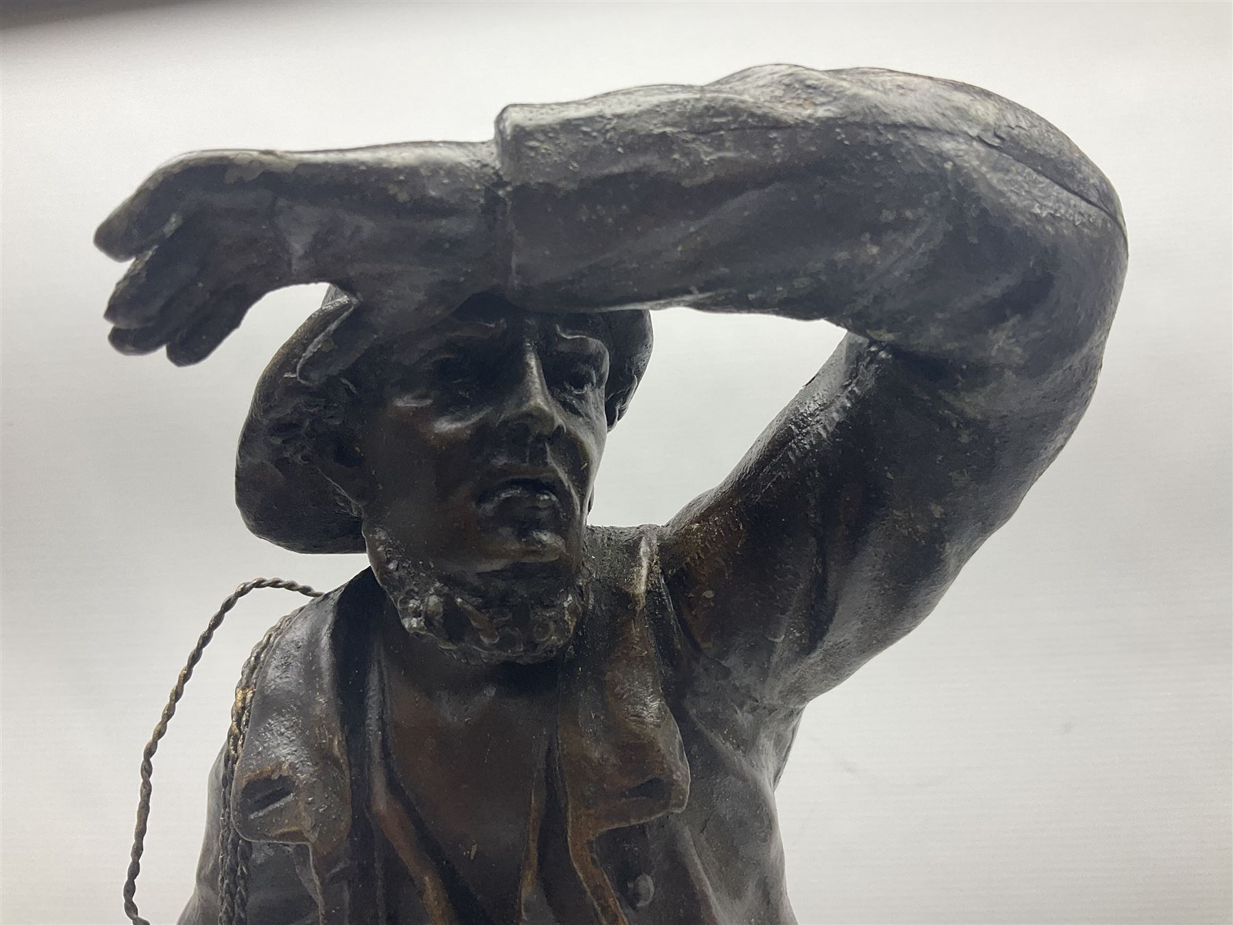Early 20th century spelter effect figure of a sailor standing in the bow of a boat scanning the horizon, on a simulated rock base with a plaque entitled 'Rescue', base fitted with a timepiece clock movement and two-part dial, with pierced hands, gilt dial centre and ivorene chapter ring written in Arabic numerals, German HAC spring driven going barrel movement wound from the front; with pendulum H65.5cm
