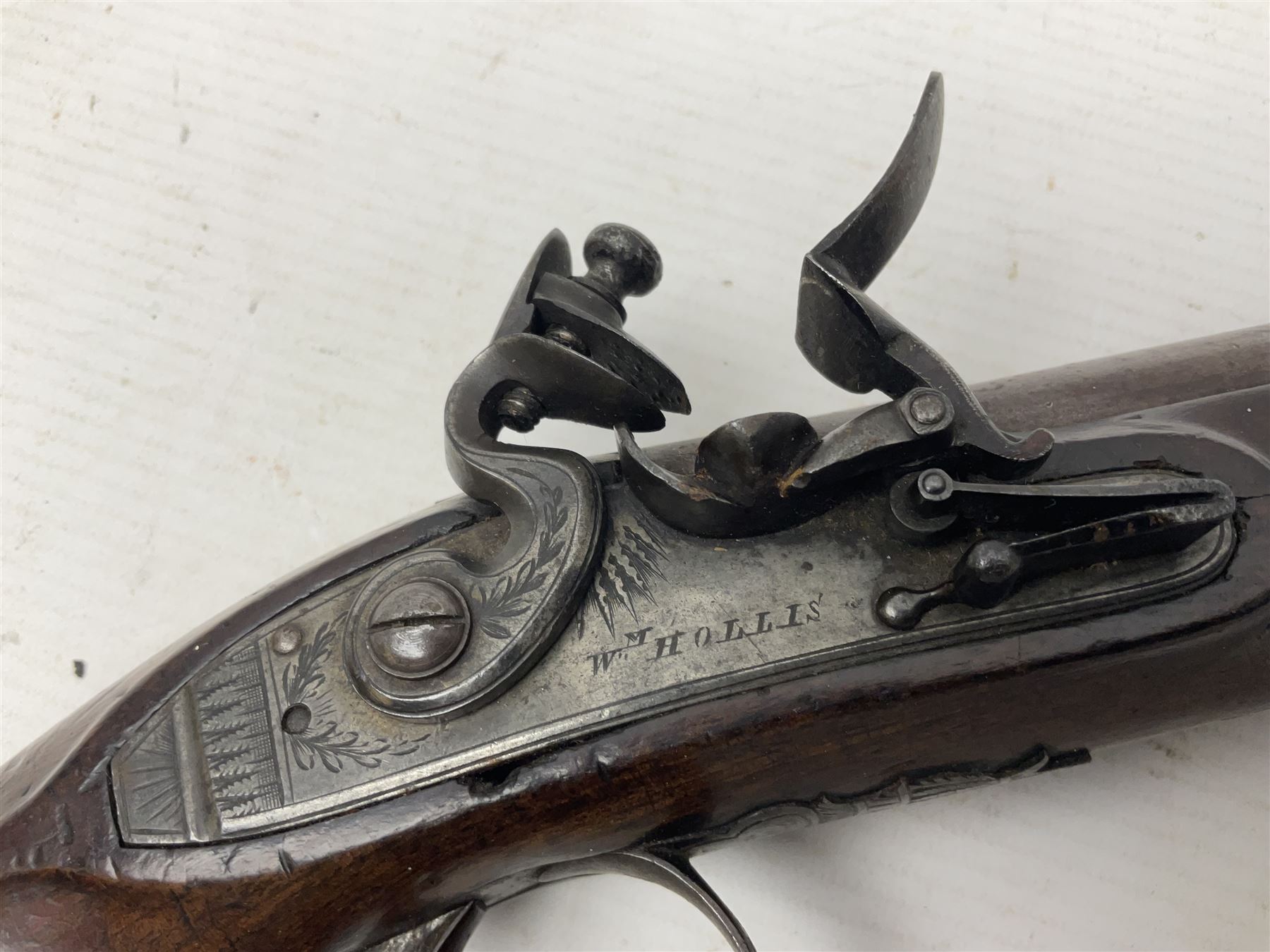Early 19th century Wm. Hollis flintlock belt or pocket pistol, approximately 20 bore, the 10cm barrel with ram rod under, engraved lock plate with maker's name and roller frizzen, engraved trigger guard with pineapple finial and walnut stock with chequered grip L25cm overall