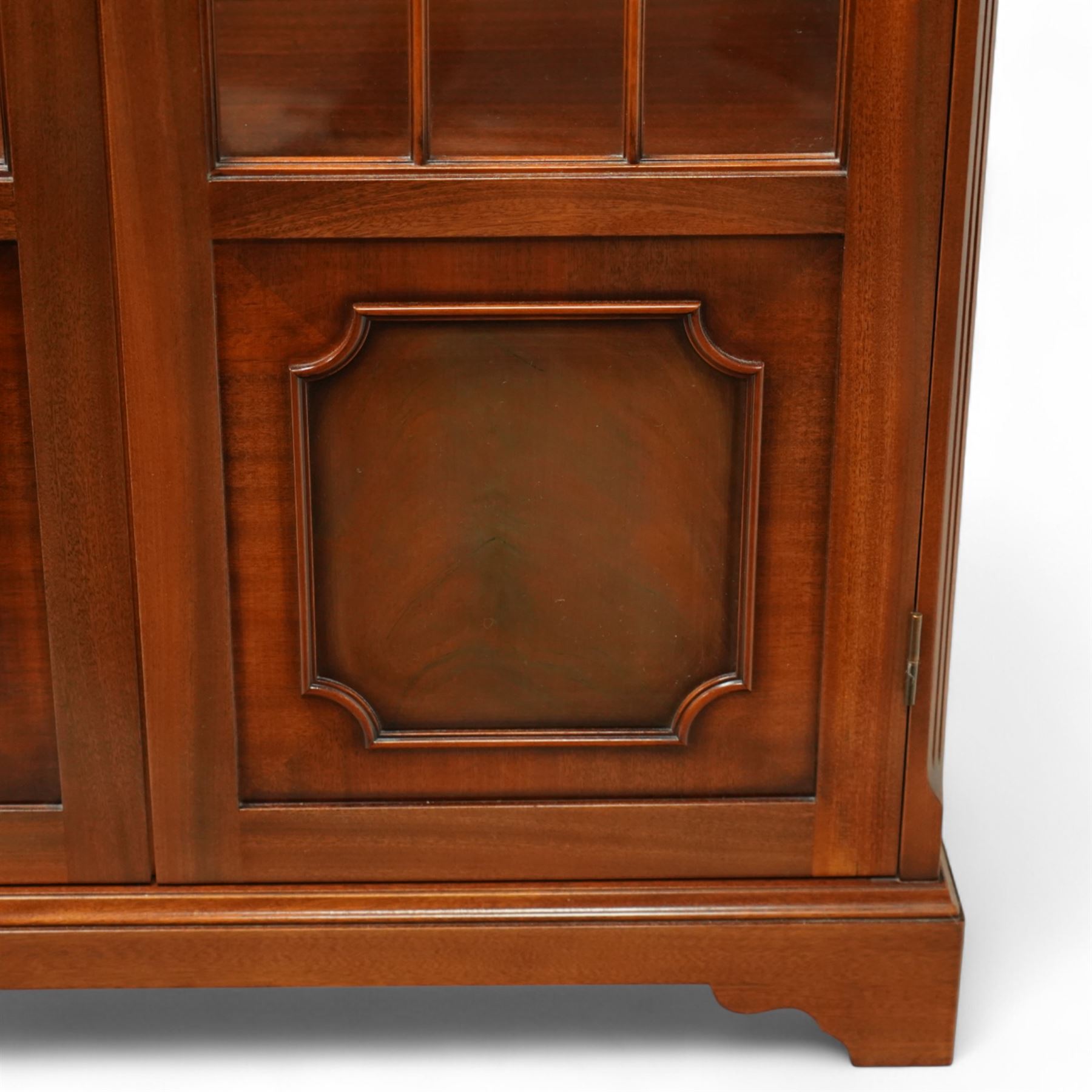 20th century Georgian design mahogany display cabinet with illuminated interior, dentil moulded cornice over twin astragal glazed doors enclosing glass shelves, lower panelled cupboard doors, on shaped bracket feet