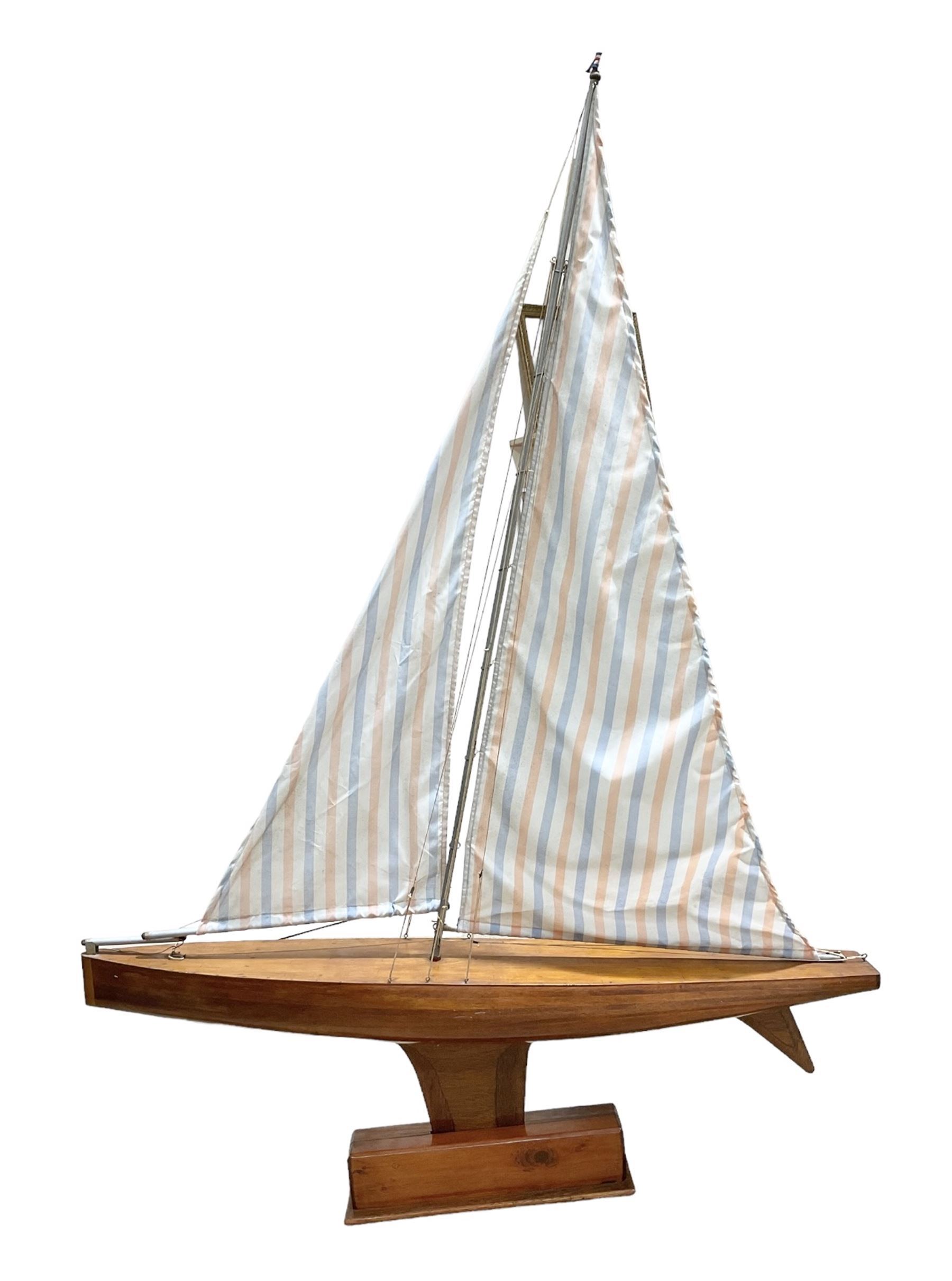 Large pond yacht with simulated planked mahogany deck, mahogany hull, wooden keel and stern fin and tubular aluminium mast with two sails; on wooden stand L131cm H on stand 177cm