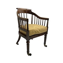 William IV rosewood tub armchair, the arched bow cresting rail over graduated bobbin turned spindles, cane seat with loose cushion, terminating in brass cups and castors.