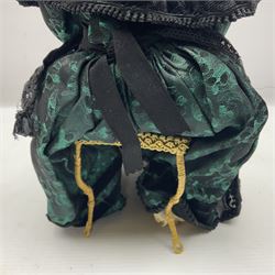 Anna Meszaros Hungary - hand made needlework figurine 'The Great Grandmother' as a pensive old lady seated on a stool wearing a long lace trimmed black and emerald green dress and hat, holding a lace handkerchief H30cm  Auctioneer's Note: Anna Meszaros came to England from her native Hungary in 1959 to marry an English businessman she met while demonstrating her art at the 1958 Brussels Exhibition. Shortly before she left for England she was awarded the title of Folk Artist Master by the Hungarian Government. Anna was a gifted painter of mainly portraits and sculptress before starting to make her figurines which are completely hand made and unique, each with a character and expression of its own. The hands, feet and face are sculptured by layering the material and pulling the features into place with needle and thread. She died in Hull in 1998.
