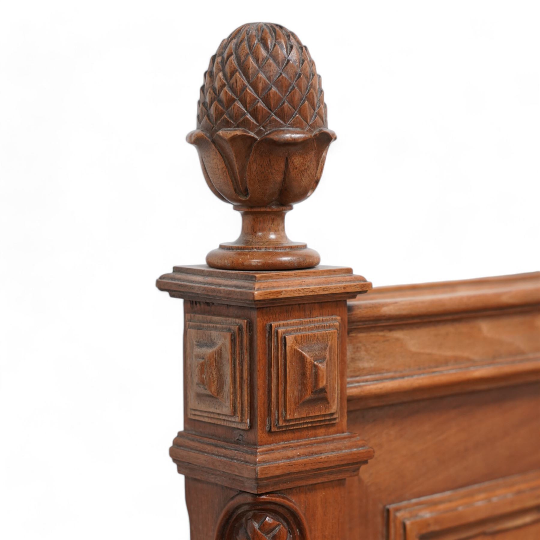 20th century French walnut 4' 6'' double bedstead, the headboard with flower head wreath pediment flanked by carved pineapple finials, reed and ribbon carved corner uprights, quarter-matched veneers, on turned feet, together with upholstered bed base