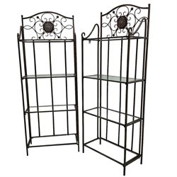 Pair of wrought metal conservatory plant stands, raised back with scrolling design, each fitted with three glass shelves