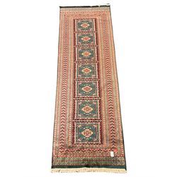 Persian red and green ground runner, the field decorated with seven square panels, five band border decorated with stylised motifs