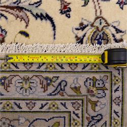 Central Persian Kashan hand-knotted carpet, ivory field densely decorated with an all-over design of scrolling floral vines and palmettes, framed by multiple borders with continuous floral meander and rosette motifs, in a palette of indigo, ivory, soft blue, sage green, rose and ochre tones, with cotton fringe ends 