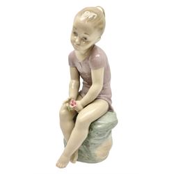 Large Nao figure modelled as a young girl seated upon a rock holding a rose, H30cm