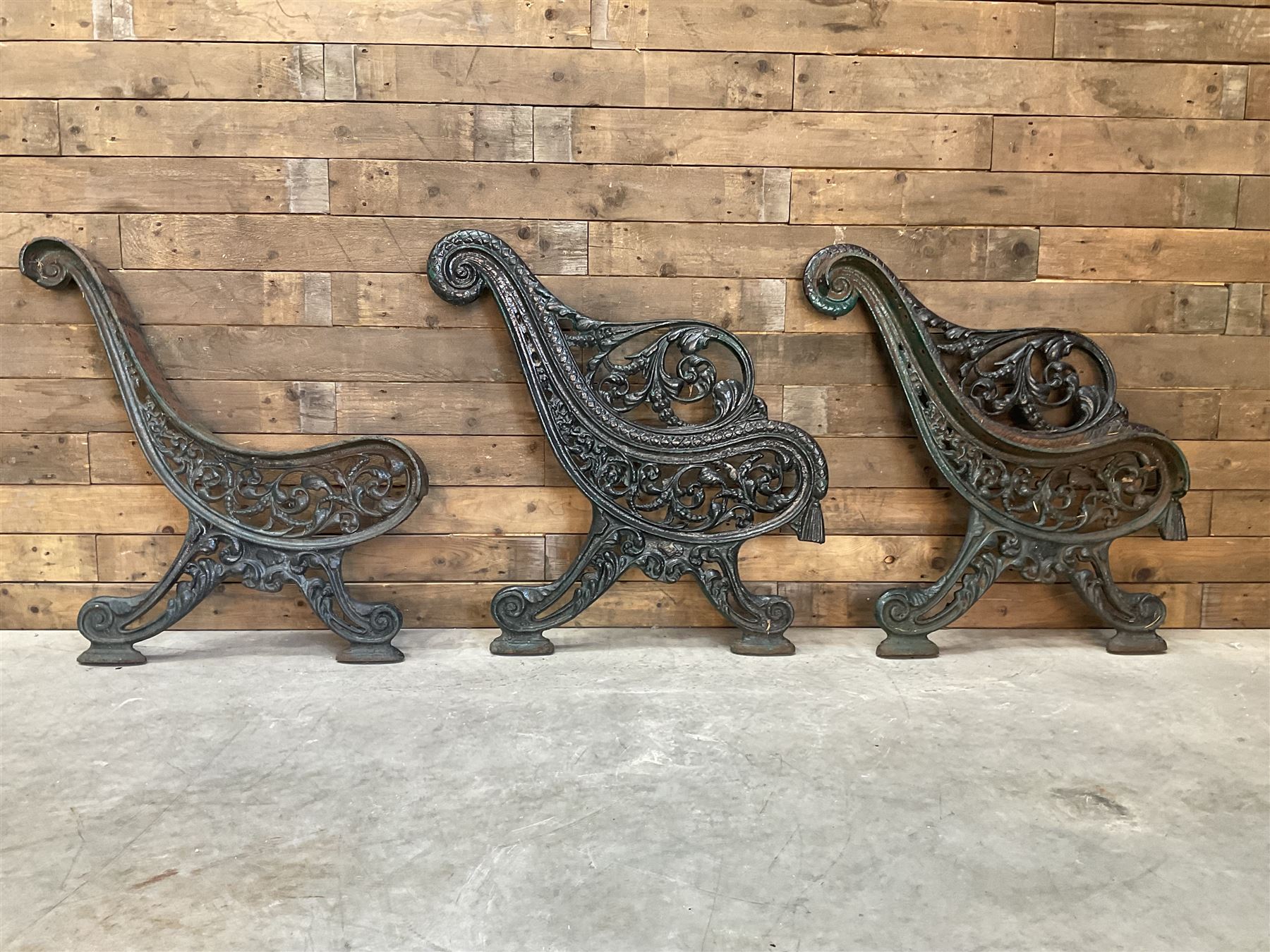 Early 20th century heavy cast iron three piece bench ends, decorated with scrolls and floral swags