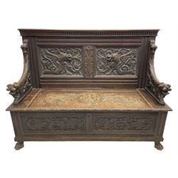 19th century oak hall bench, dentil cresting rail over moulded frame with panelled back carved with fire-breathing mythical beasts and central acanthus leaf motif, scroll carved down-sweeping arms carved with grotesque masks with scrolled foliage and shells, hinged box seat carved with scrolling foliage over panelled front with further carved foliage decoration, on paw carved front feet 
