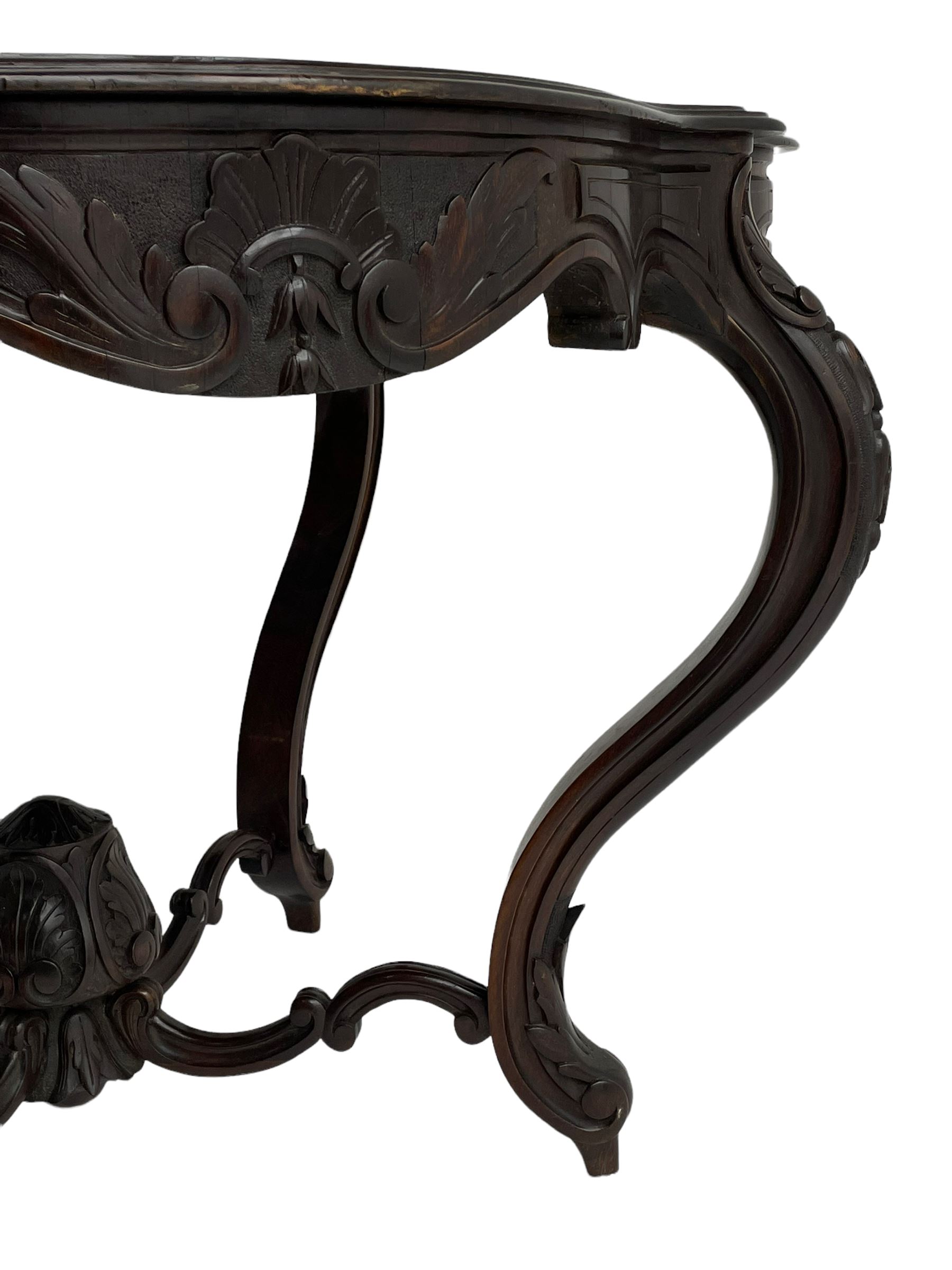 19th century Irish rosewood centre table, the shaped and moulded top over shaped apron carved with scrolled foliage, on serpentine supports carved with bell flowers, the supports united by anthemion carved finial and s-scroll x-framed stretchers