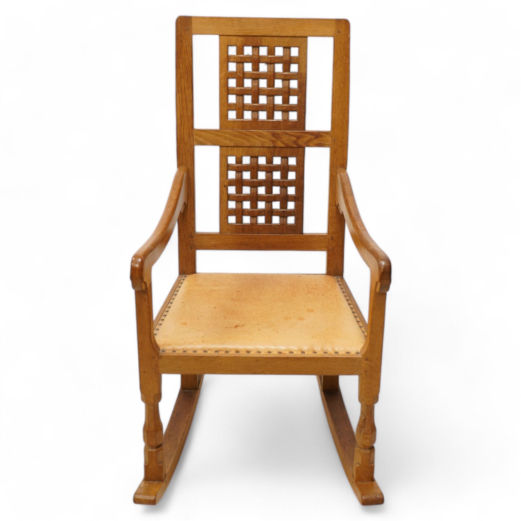 Mouseman - oak rocking armchair, double pierced and carved high lattice back, upholstered in tan leather with stud work, raised on octagonal front supports, carved with mouse signature, by the workshop of Robert Thompson, Kilburn

Provenance - this lot comes to us for sale from direct descent of Robert Thompson. Thompson is the great grandfather of the vendor.