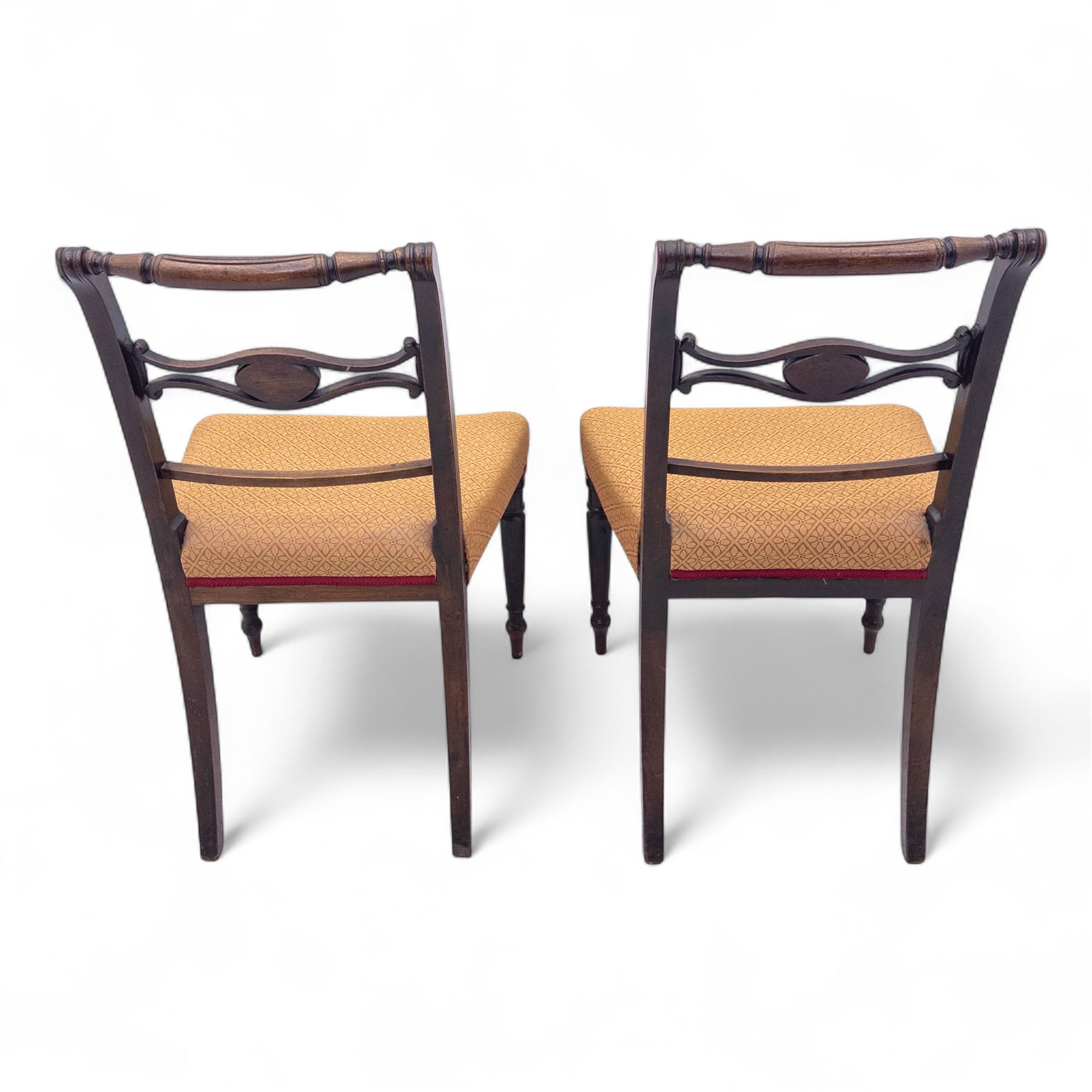 Pair of Regency mahogany side chairs, reeded bar backs centred by oval paterae, overstuffed seats upholstered in gold geometric patterned fabric, on turned tapering front supports 