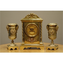  Late 19th/early 20th century brass clock garniture, architectural cased clock with twist columns, Arabic dial signed 'Pearce & Sons, Leeds', twin train movement striking the hours on coil, urn shaped garnitures mounted with cherubs and winged motifs  