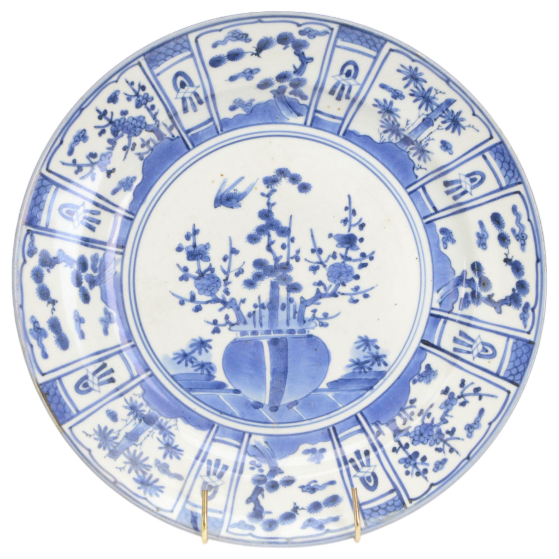 Two Japanese Edo period Ko Imari blue and white porcelain chargers, each decorated in the Kraak style with urns issuing peonies, pine and prunus, within panelled borders containing flowers, tress and precious objects, each approximately D 31.5cm