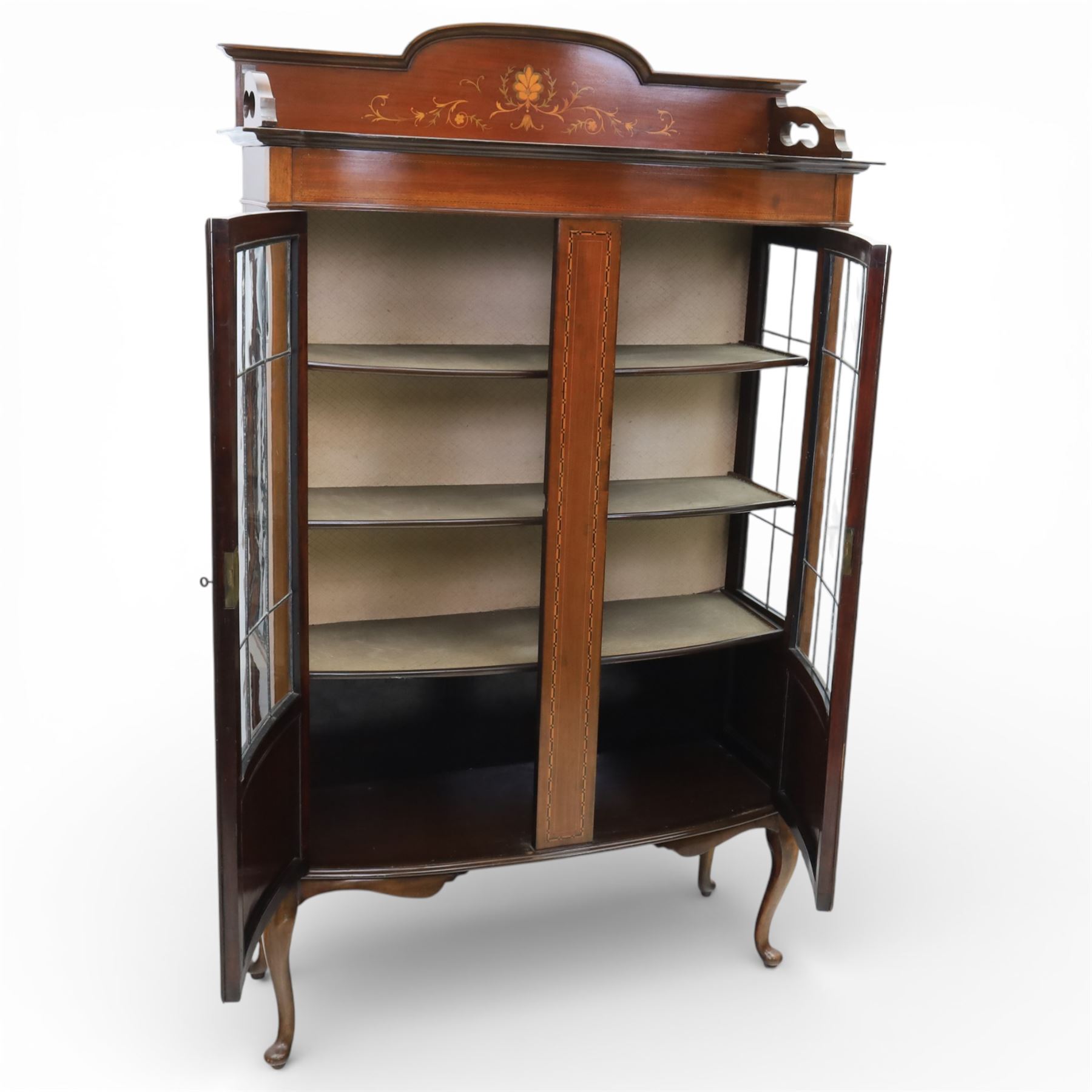 Edwardian mahogany display cabinet, arched back with satinwood and harewood marquetry foliate decoration above a moulded cornice, serpentine front fitted with twin glazed doors with astragal bars, the lower door panels inlaid with oval reserves, standing on elegant cabriole legs terminating in pad feet
