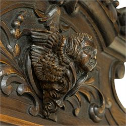 Large mid-19th-century Victorian rococo revival carved oak overmantel mirror, the rectangular mirror frame carved in high relief,  arched and scrolled pediment surmounted by a central foliate spray with acanthus scrolls above a finely carved classical mask, frieze decorated with symmetrical  acanthus scrolling, vertical uprights carved with trailing foliage, flowers, and ribbon-tied elements, terminating on a square supports 