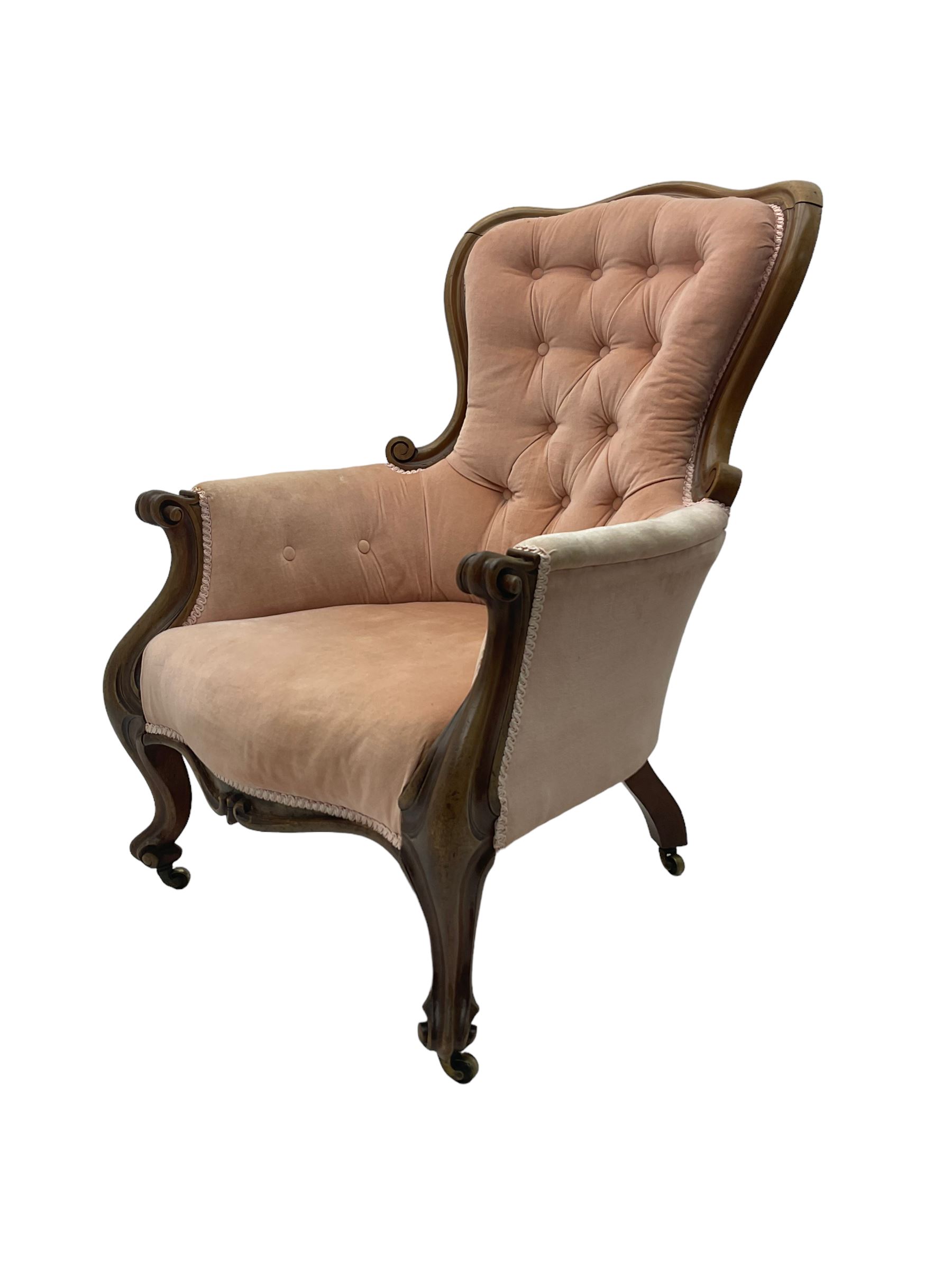 Victorian walnut framed armchair, shaped back with carved and scrolled arm terminals, upholstered in buttoned pale pink fabric, raised on cabriole supports terminating in castors