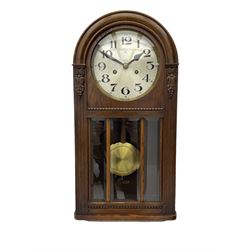 German HAC “ting tang” quarter striking wall clock in a round arched oak case with applied carving and beadwork, glazed door with a visible pendulum and silvered 24-hour dial with Arabic numerals and steel spade hands,  8-day spring driven movement striking on gong rods.

