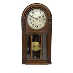 German HAC “ting tang” quarter striking wall clock in a round arched oak case with applied carving and beadwork, glazed door with a visible pendulum and silvered 24-hour dial with Arabic numerals and steel spade hands,  8-day spring driven movement striking on gong rods.

