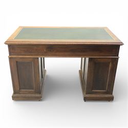 Victorian oak pedestal desk, the rectangular top with inset green leather writing panel and decorative gilt border, over a central frieze drawer flanked by two short drawers, twin pedestals each fitted with four drawers with brass handles, arched kneehole opening, standing on moulded plinth bases