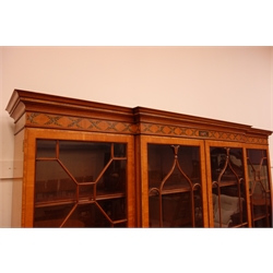 Sheraton Revival satinwood breakfront bookcase, frieze painted with scrolling leafage above four astragal doors with adjustable shelves, the base with four doors painted with floral sprays in oval panels, on a plinth base, W234cm, H235cm, D52cm