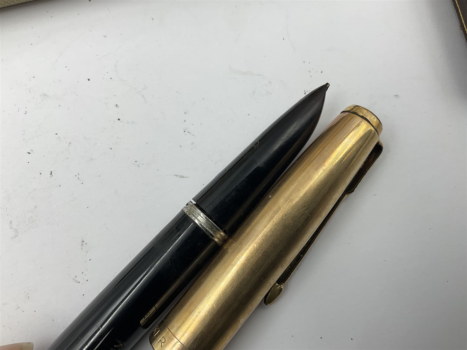 Three parker fountain pens, one example with 14ct gold plated cap and personal engraving, in Parker 51 box, together with a silver Sampson Mordan Everpoint propelling pencil with personal engraving and a silver cased fountain pen with 14ct gold nib and a souvenir bronze Dollfus-Mieg medallion, awarded to John G Sedorski, in fitted case 