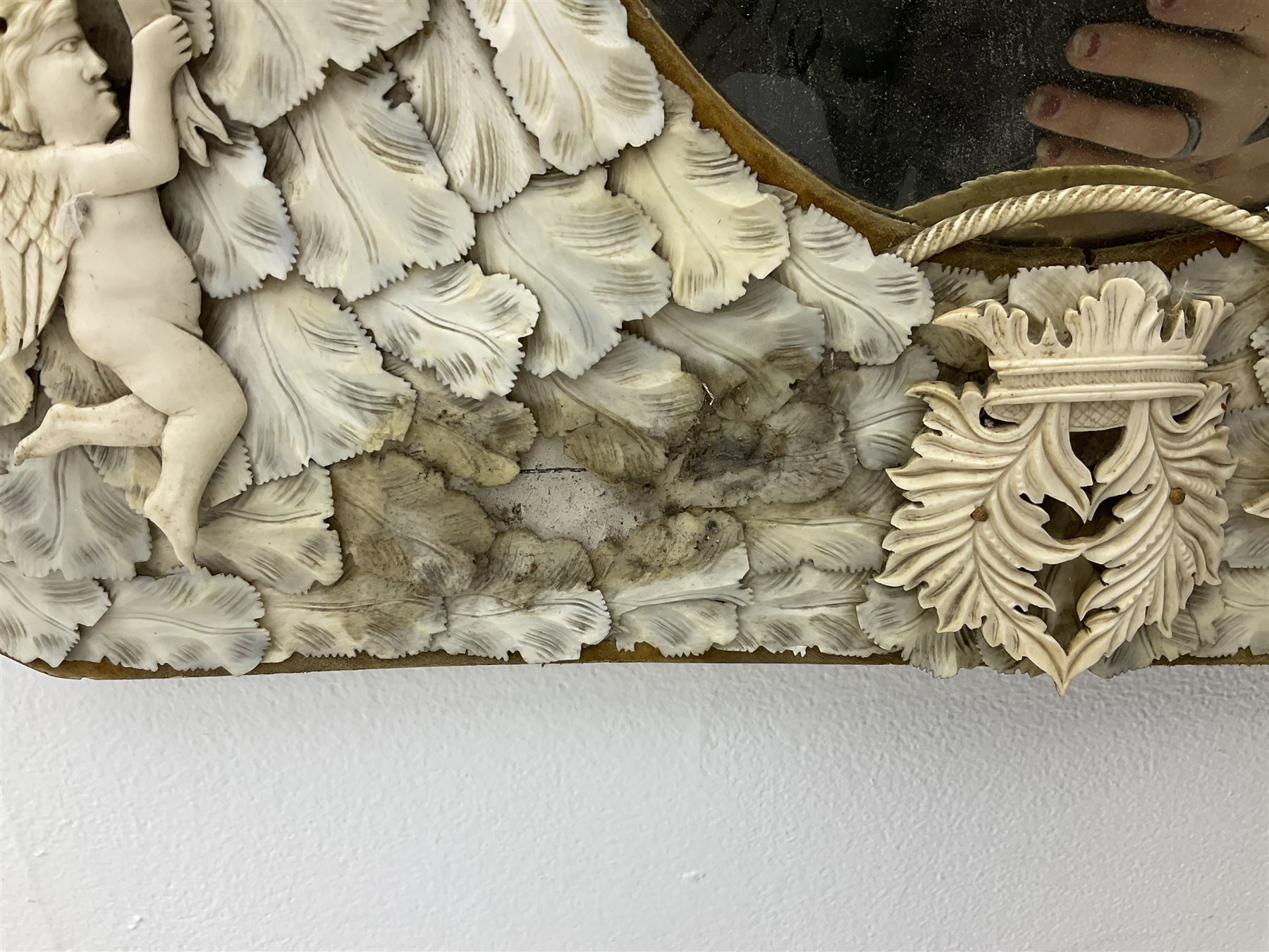 Pair 19th century French Dieppe bone and ivory wall mirrors, the oval bevelled mirror plates within rectangular frames with shaped tops, profusely decorated with ivory leaves, further detailed with carved bone armorial type crest inscribed 'SGOTORVM', putti, fish and mask heads, H81cm W48cm