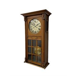 A 1930’s German eight-day spring driven wall clock by Philipp Hass & Sohne striking the hours and half hours on a gong, with an eight-inch silvered dial with a spun brass bezel, Arabic numerals, minute track and steel spade hands, in a flat-topped oak case with full length door and applied mouldings, nine glazed panels with a visible spun brass pendulum. With key.                                   