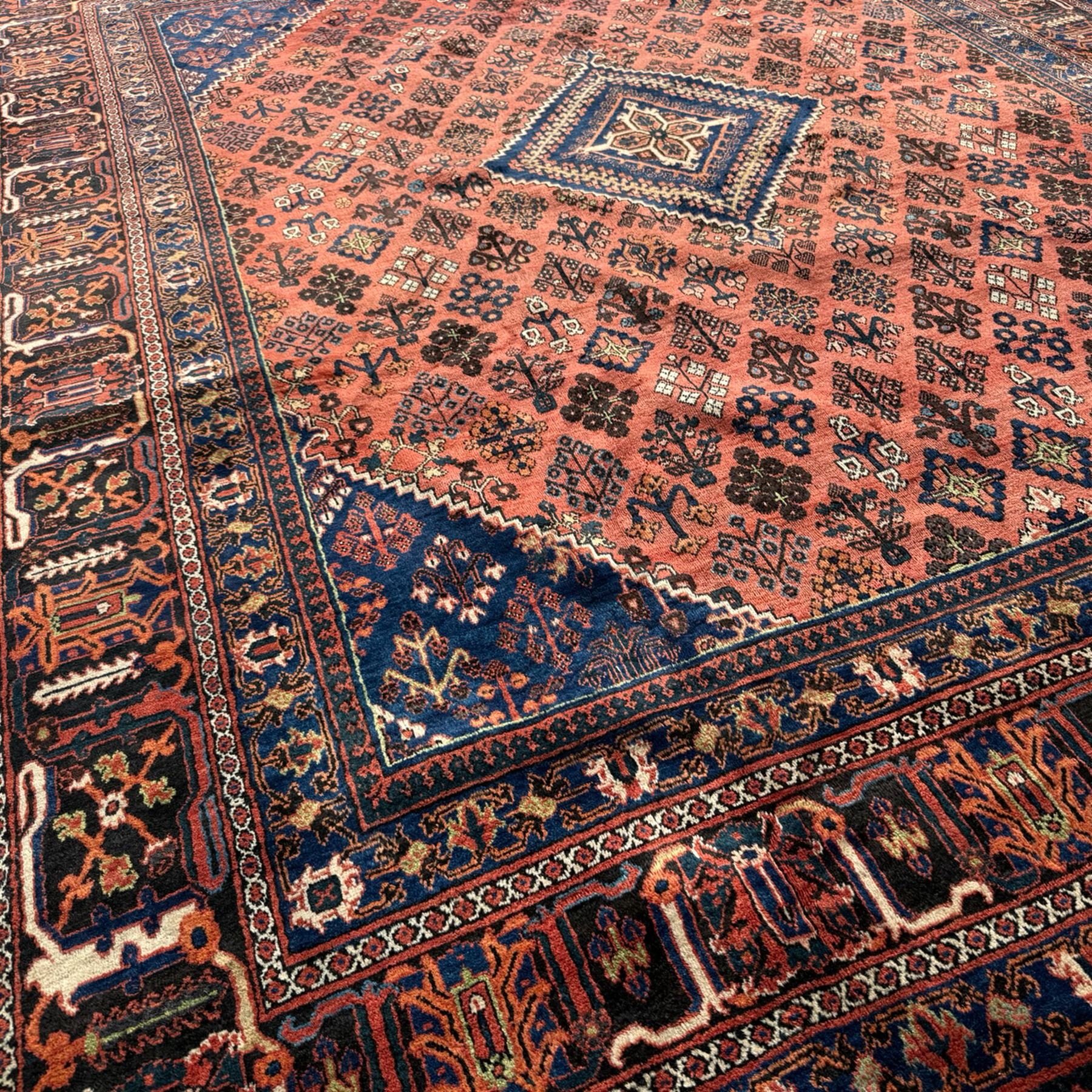 Joshgan Persian wool rug, with diamond-framed medallion, on a deep red field filled with geometric-shaped floral motifs and indigo-filled spandrels 
