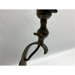 Arts & Crafts Jesson, Birkett & Co, brass table lamp or wall light, designed by Thomas Birkett, the tapering stem with adjustable ball pivot supporting a conical shade with tapering final with ball terminal, upon a circular domed base pierced for wall mounting, shade positioned upright overall H57cm

Often misattributed to Arthur Stansfield Dixon for Birmingham Guild of Handicraft, this particular lamp was designed by Thomas Birkett.
In the late 1890's Birkett worked as a metalwork at the Birmingham Guild, before later joining the Faulkner Bronze Company which went on to become Jesson, Birkett & Co in 1904. The lamp features in lighting catalogues from the firm under the model no E490.

