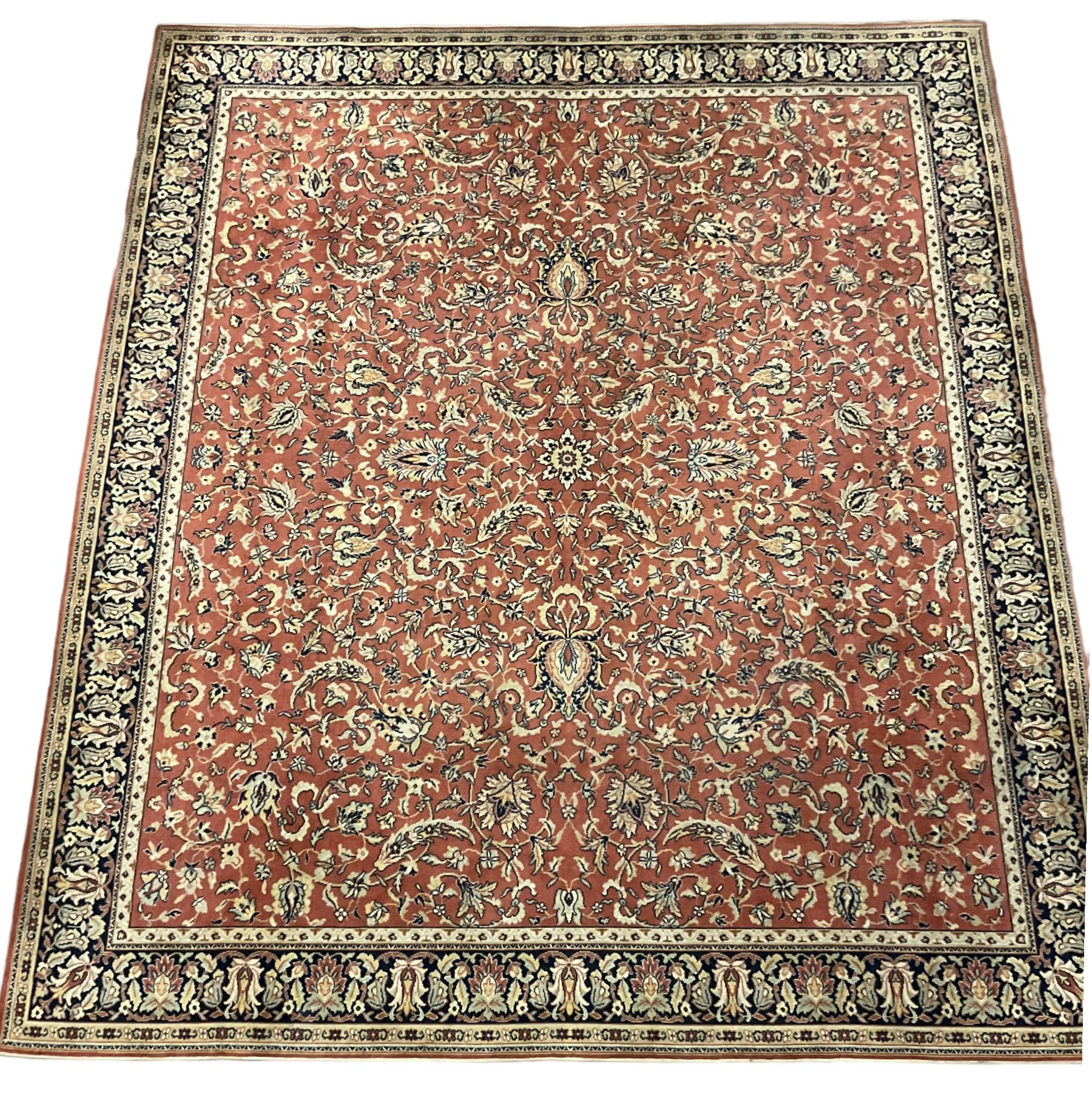 Large Persian design red ground rug, the field decorated with interlacing branches and stylised plant motifs, repeating border with further plant and floral motifs