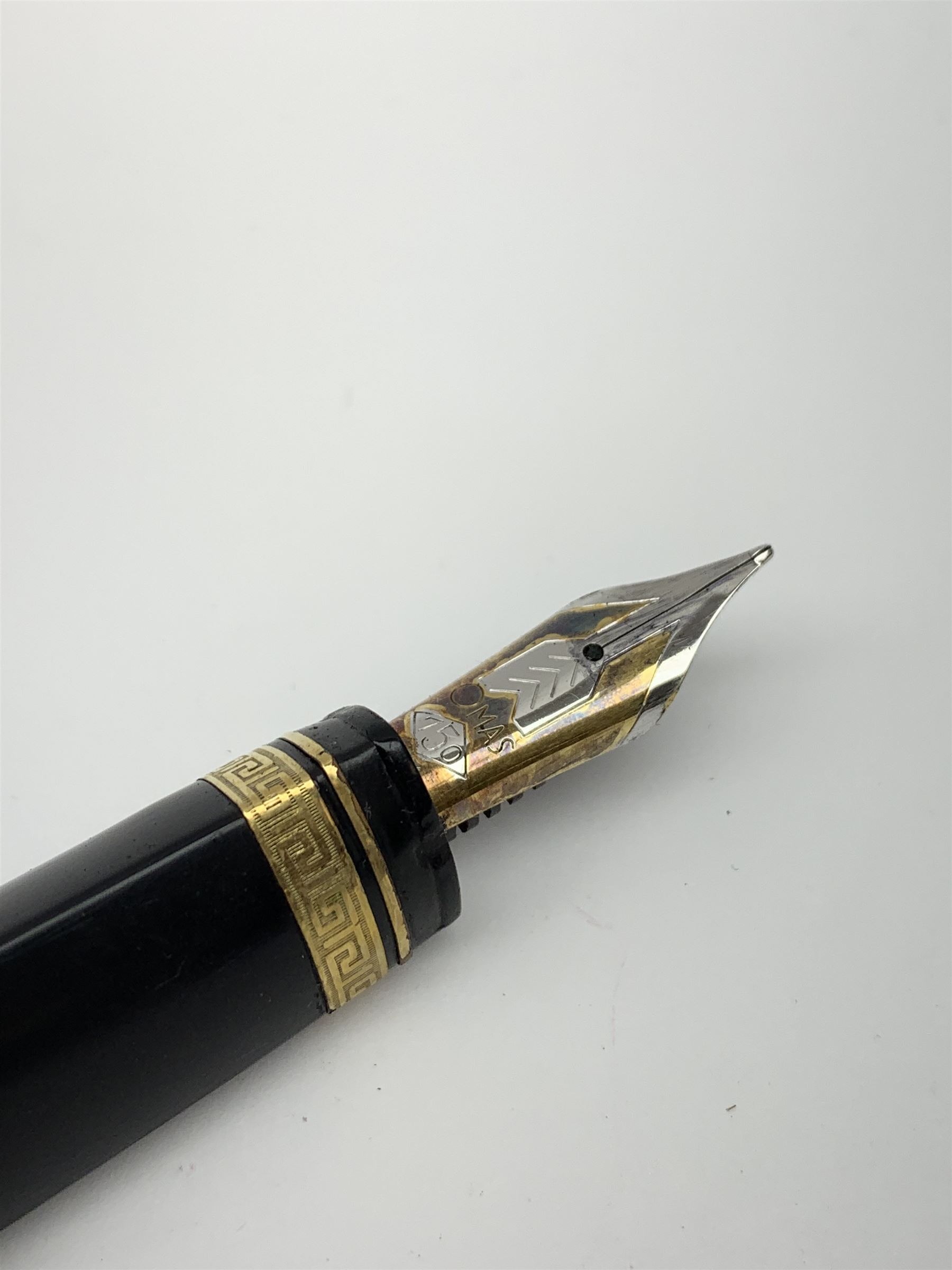 An Omas 360 fountain pen, the black triangular section body with gold coloured clip and banding, and Greek Key border to the cap, the bicolour nib marked 750 18K.