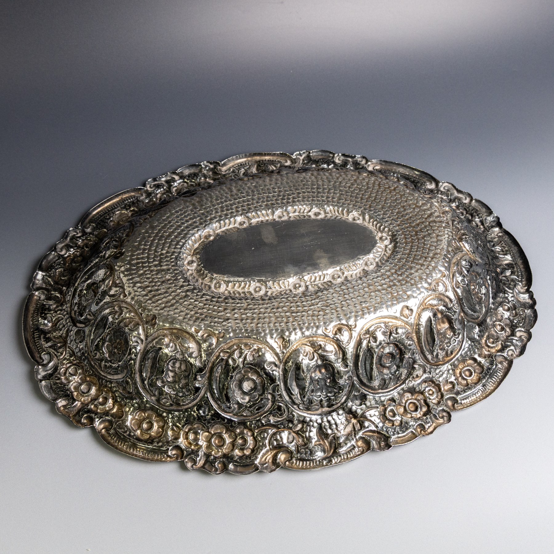 Late 19th/early 20th century continental silver serving bowl, of oval form, profusely embossed with scrolling floral and foliate decoration, with hammered finish to interior