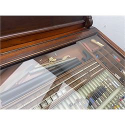 Edwardian mahogany artist's cabinet once belonging to the British artist Eli Marsden Wilson (1877-1965), raised panelled back mounted by carved brackets, sloped and hinged glazed lid enclosing paint holders and compartments, up-and-over panelled door revealing three slides, fitted with two banks of five graduating drawers with recessed brass handles, on skirted base.

Together with a quantity of artists' equipment and tools including paints, paintbrushes, charcoal, chalks, etc. and various prints relating to the life of the artist, including Quaker anti-war posters, Victorian Stevengraphs, and various chromolithographs 

Provenance: Removed from the studio of Eli Marsden Wilson. The cabinet comes to us for sale through family descent. The vendor is descendant of Marsden. Many further etchings removed from the cabinet are being sold in the Spring Art Sale, Friday 15th March 2024, Lots 265-271.

Notes: born in Ossett, Eli Marsden Wilson was the only son of Alfred Wilson, a foreman beamer, and Emma Marsden, and had five sisters. After studying at Wakefield College of Art, he moved to the Royal College of Art in London, where he became a pupil of Sir Frank Short. He had his first exhibit at the Royal Academy in 1905, the same year he married fellow artist Hilda Mary Pemberton.

A Quaker, vegetarian, and pacifist, he was a conscientious objector in World War I and as such was imprisoned in 1917 for two years. In September 1922 he was commissioned by Princess Marie Louise to produce miniature etchings for Queen Mary's Dolls' House at Windsor Castle; two such etchings are being sold in the Spring Art Sale, Friday 15th March 2024, Lot 265.