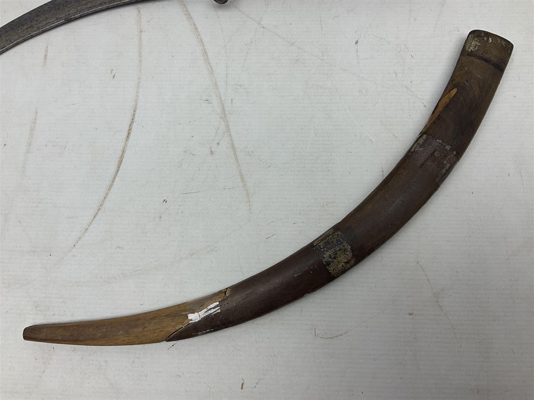 Late 19th/early 20th century Moroccan nimcha dagger-sword, the 40cm curving steel blade with engraved decoration on both sides; shaped hardwood hilt inlaid with brass, white metal wires and red coloured panels; in similarly inlaid scabbard L61cm overall