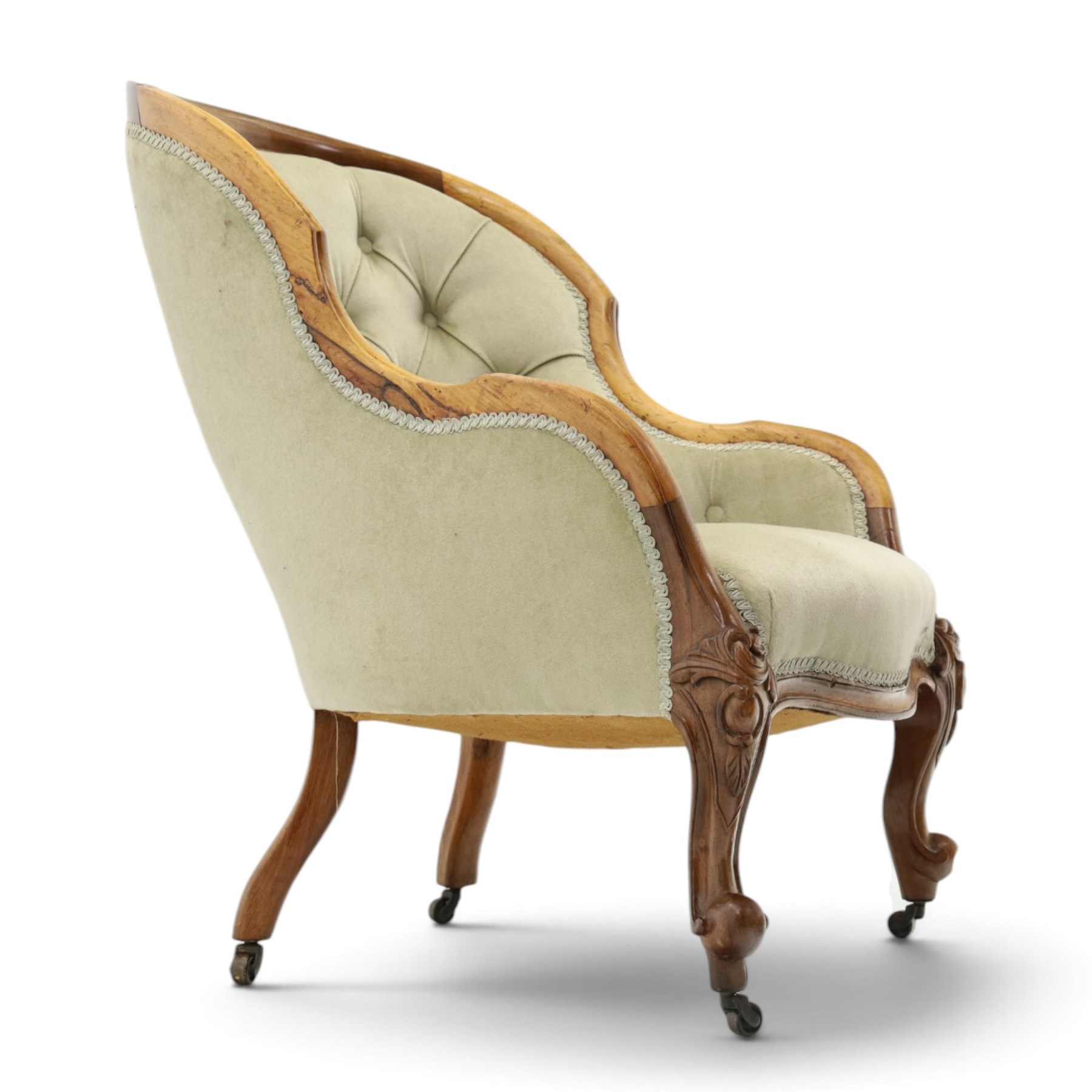 Victorian carved walnut framed armchair with matching stool, the tub-shaped chair with moulded and shaped frame and arm terminals, raised on scrolled cartouche carved supports with scroll feet and castors, buttoned back and sprung seat upholstered in sage green fabric; the small circular footstool with buttoned seat and scroll supports (W36cm H15cm)