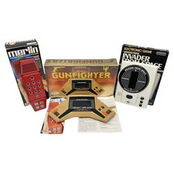 Three late 70s/early 80s handheld electronic games; Bandai Electronics Arcade ‘Gunfighter’ (1980), Grandstand ‘Invader From Space’ (1980), Palitoy ‘Merlin The Electronic Game Machine’ (1979) with game sheet and instruction booklet, all with original boxes (3) 