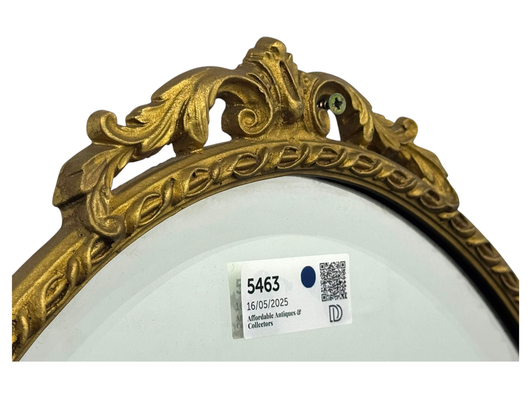 Oval gilt wall mirror, with bevelled edge plate within a moulded frame cast with acanthus scrolls and foliate decoration, pierced cartouche crest and apron, flanked by scrollwork handles
