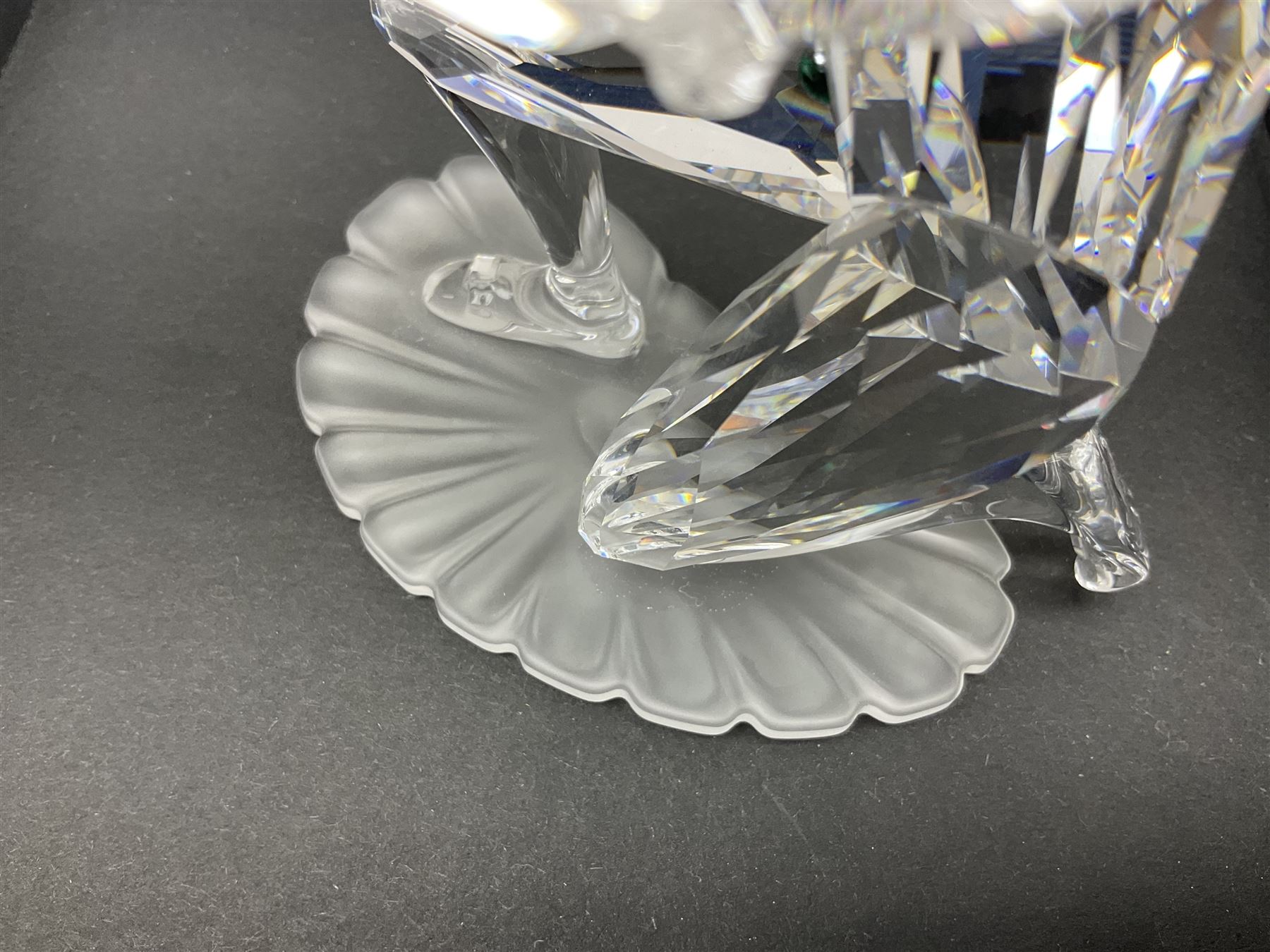 Swarovski Crystal Masquerade trilogy; 1999 Masquerade Pierrot, 2000 Columbine, 2001 Harlequin all with accompanying plaque, stand and original box, together with a glass display case with mirrored back and sides 